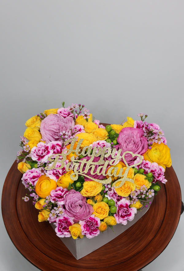 Beautiful heart shaped box with fresh flowers . Yellow ranunculus, purple roses, wax flower, mini carnations, and yellow spray roses all in a heart shaped box. Local delivery available to Conroe, The woodlands, Spring, Willis and surrounding areas. Delivery available to St lukes hospital, The Woodlands Methodist and Memorial Hermann. 